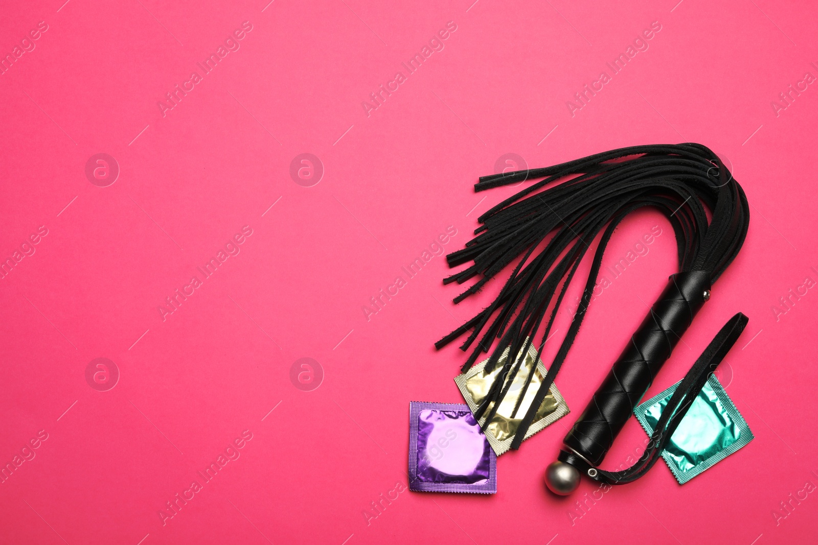 Photo of Whip and condoms on pink background, top view with space for text. Sex game