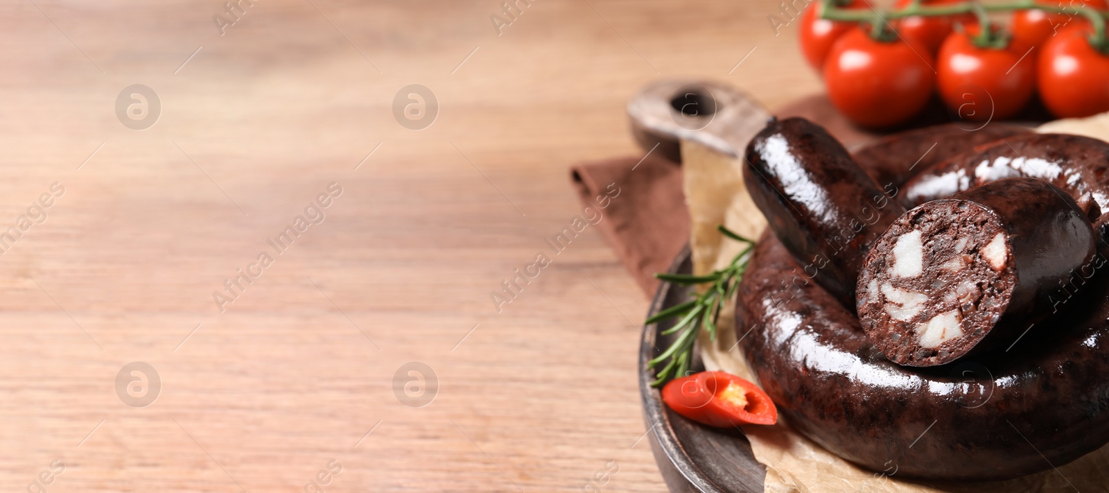 Photo of Tasty blood sausages served on wooden table, closeup. Space for text