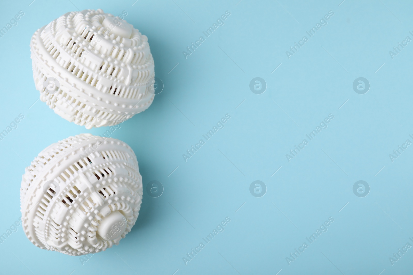 Photo of Laundry dryer balls on light blue background, flat lay. Space for text