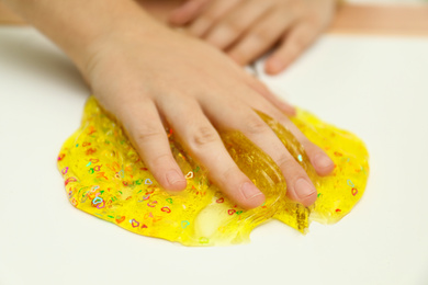 Little child playing with slime at white table, closeup