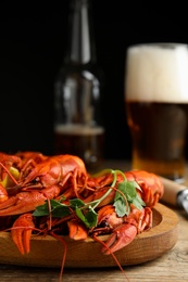 Delicious red boiled crayfishes and beer on wooden table, closeup