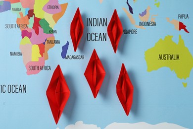 Red paper boats on world map, flat lay