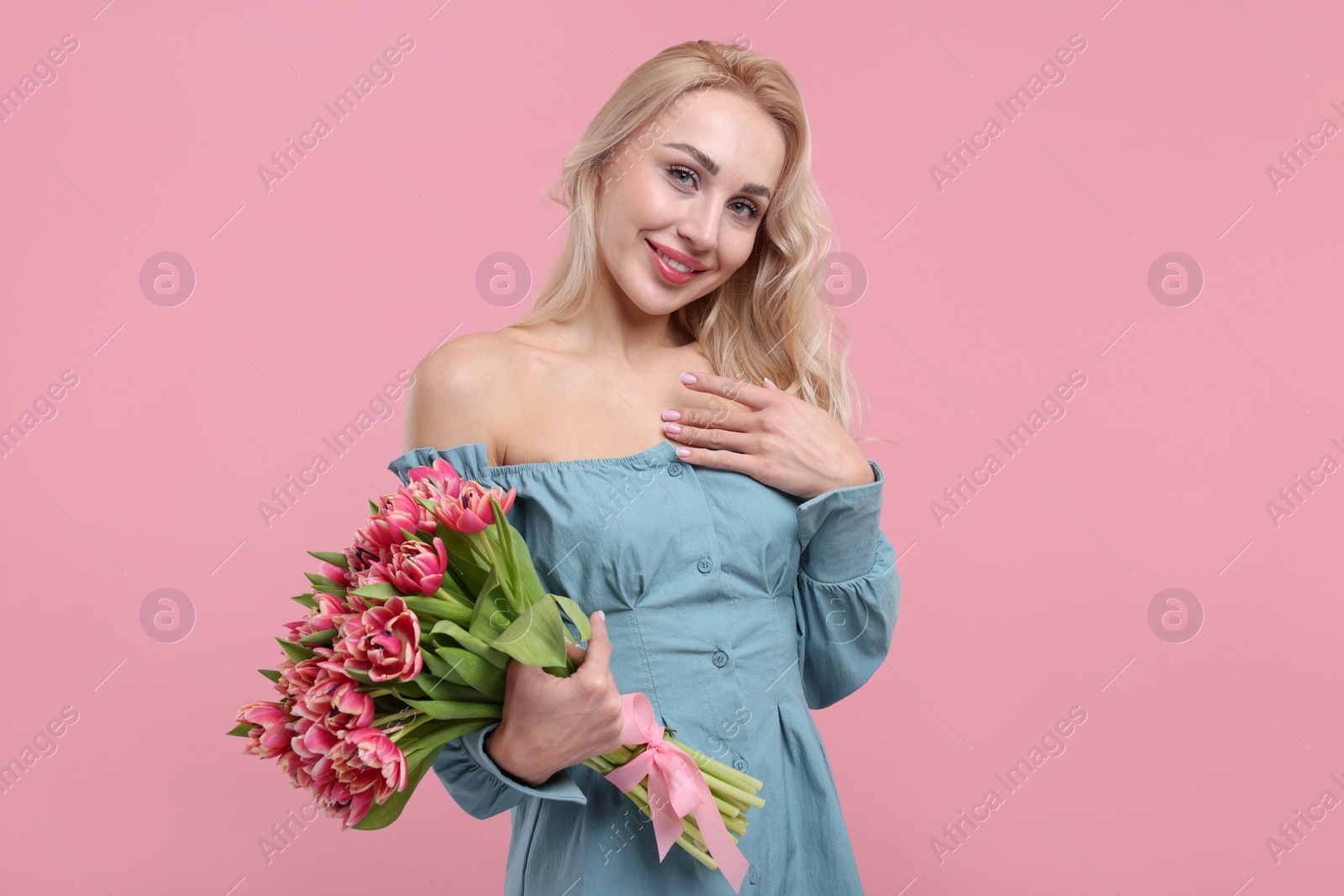 Photo of Happy young woman with beautiful bouquet on dusty pink background