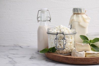 Photo of Different dairy products and mint on white marble table, space for text