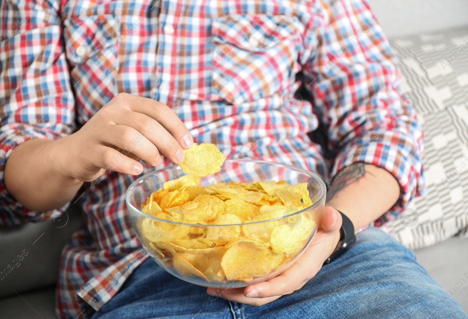Photo of Man eating chips while watching TV, closeup view