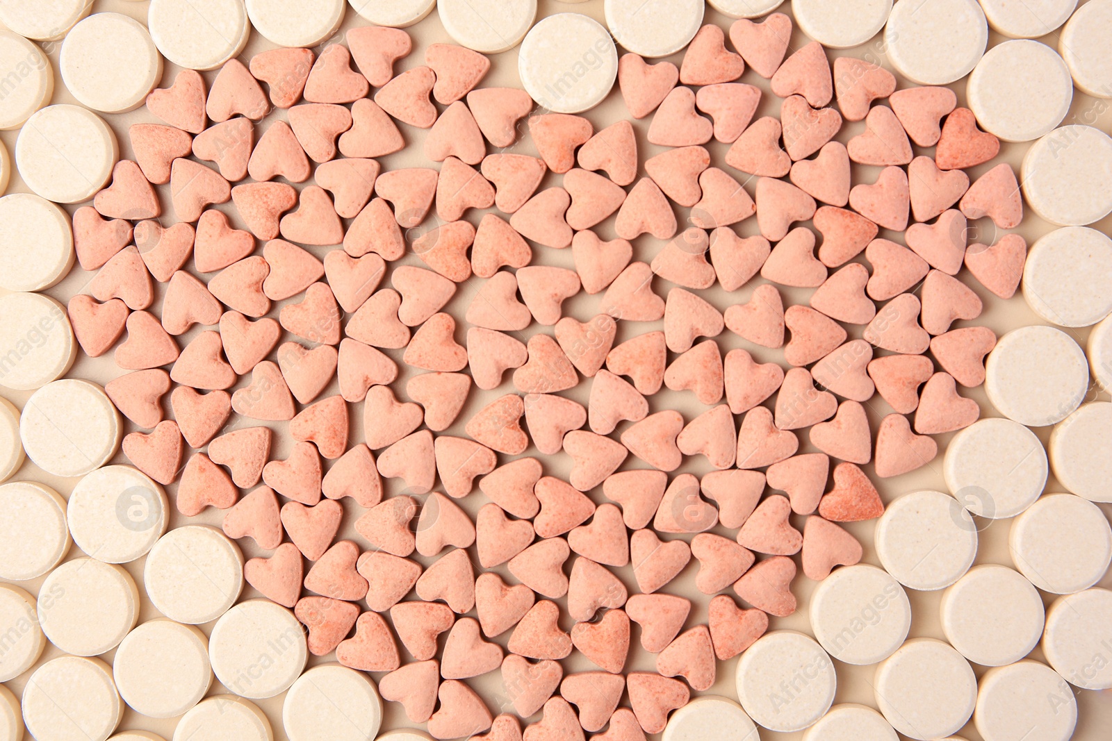 Photo of Heart made of vitamins for pets on beige background, flat lay