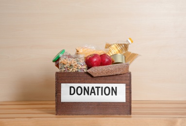 Photo of Donation box with food on table against light background