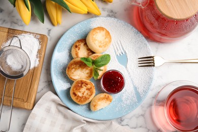 Delicious cottage cheese pancakes with jam and icing sugar on white marble table, flat lay