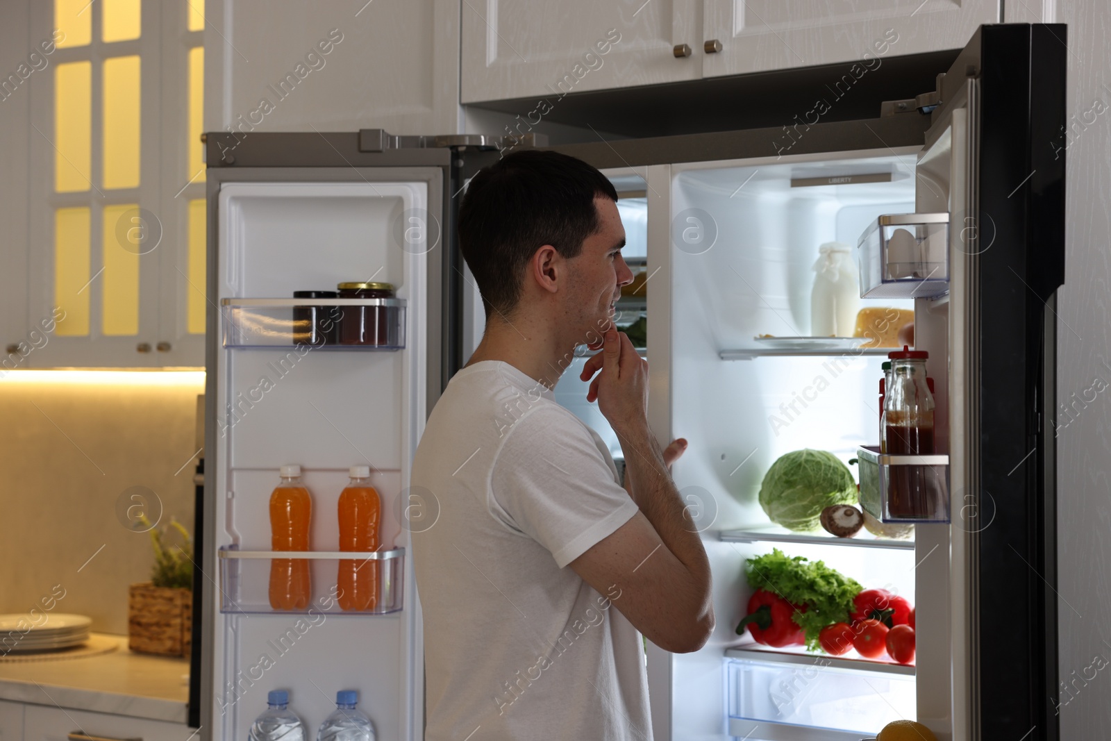 Photo of Happy man near refrigerator in kitchen at home