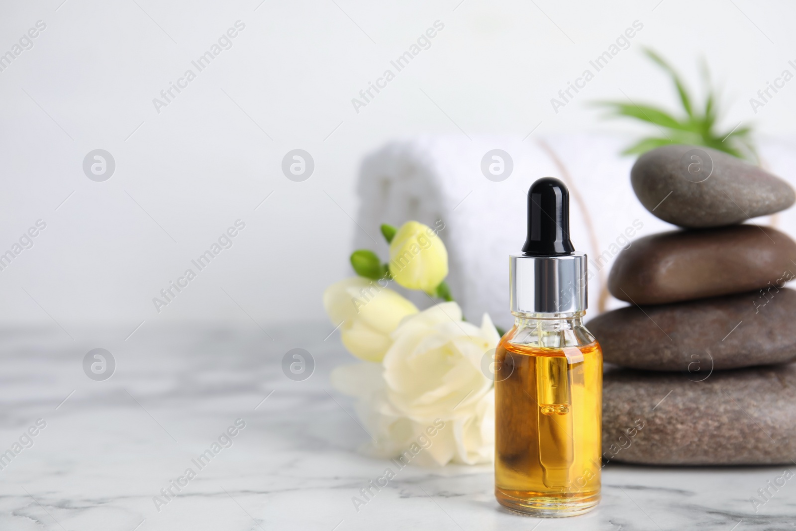 Photo of Bottle with essential oil on white marble table, space for text. Spa product