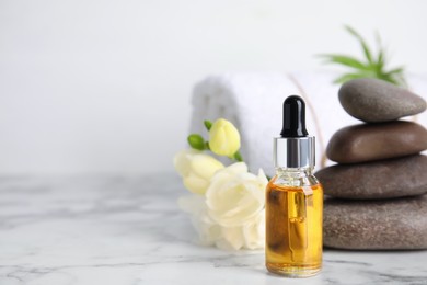 Photo of Bottle with essential oil on white marble table, space for text. Spa product