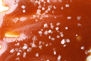Photo of Delicious caramel sauce with sea salt on white background, closeup