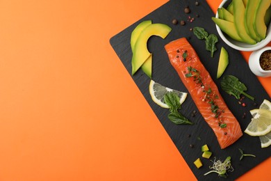 Photo of Delicious salmon with spinach, lemon and avocado on orange background, flat lay. Space for text