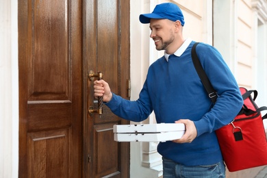 Male courier with order at entrance. Food delivery service