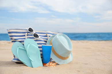 Different stylish beach objects on sand near sea