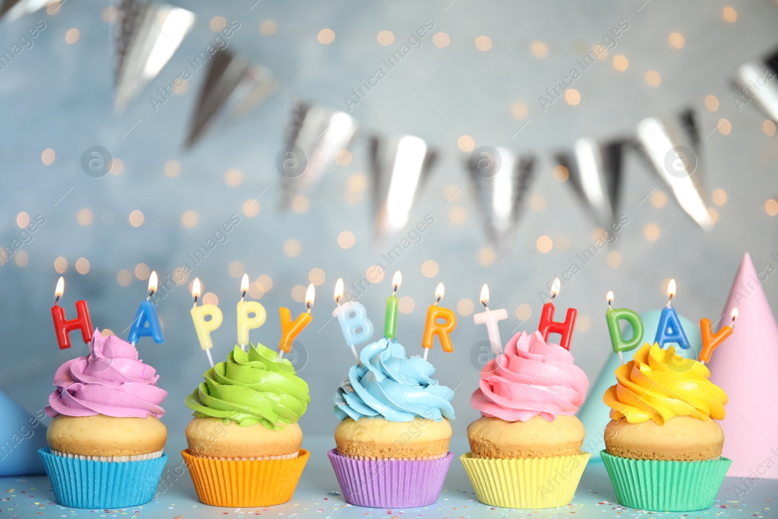 Photo of Birthday cupcakes with burning candles on grey table