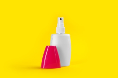 Photo of Bottle with insect repellent spray on yellow background