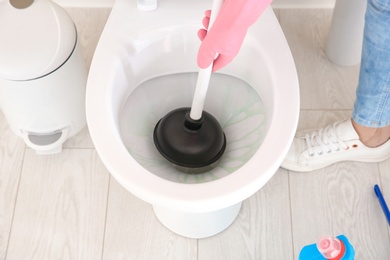 Photo of Woman cleaning toilet bowl in bathroom