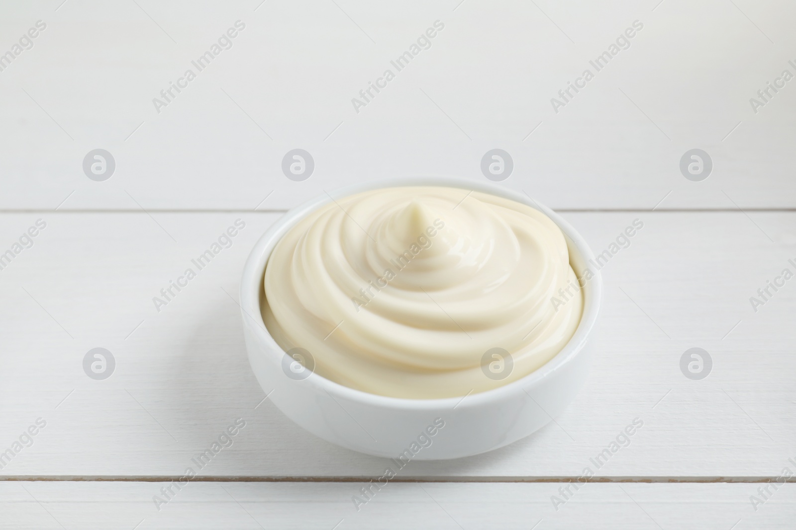 Photo of Fresh mayonnaise sauce in bowl on white wooden table