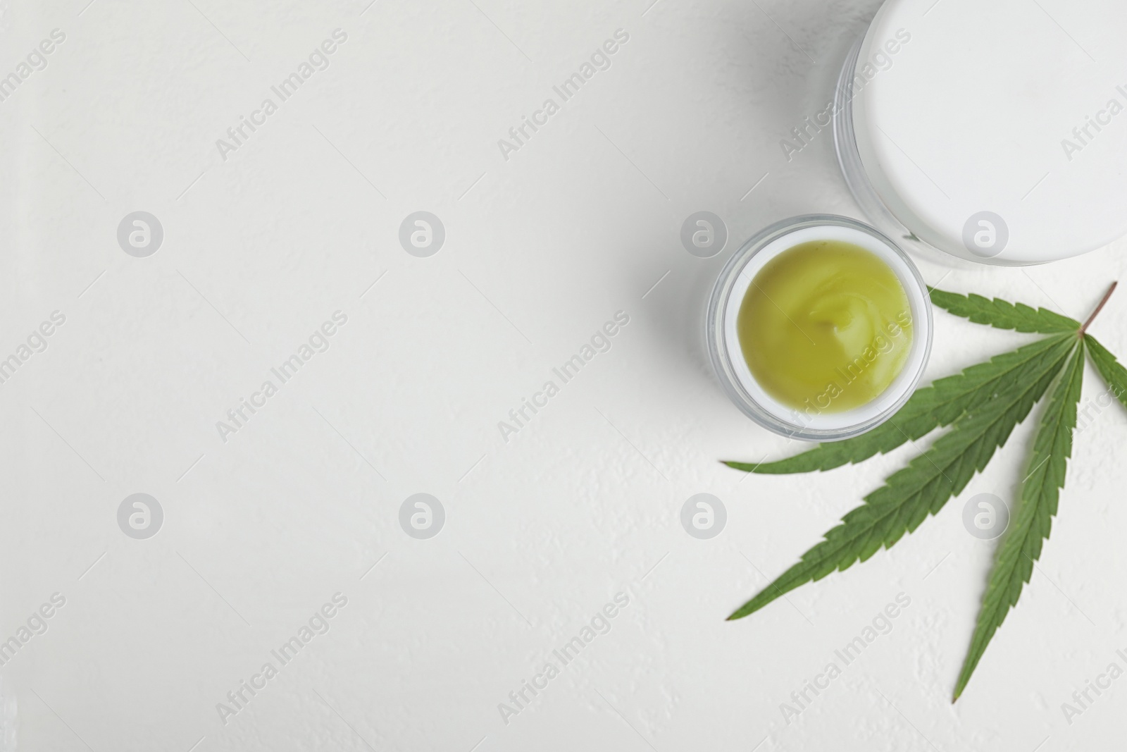 Photo of Jars of hemp cream on white table, flat lay with space for text. Organic cosmetics