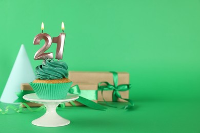 Photo of Delicious cupcake with number shaped candles on green background, space for text. Coming of age party - 21th birthday