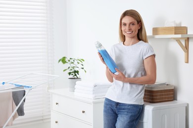 Photo of Woman holding fabric softener in bathroom, space for text