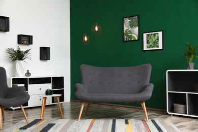 Photo of Modern living room interior stylish sofa near green wall