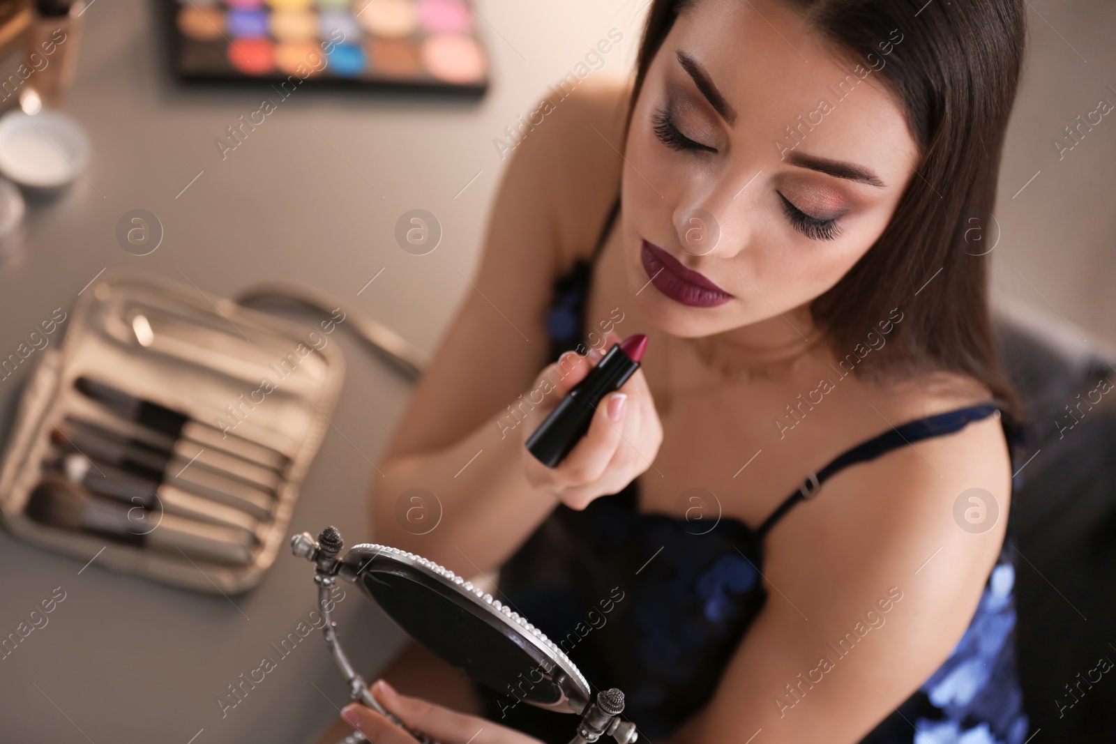 Photo of Portrait of beautiful woman applying makeup indoors