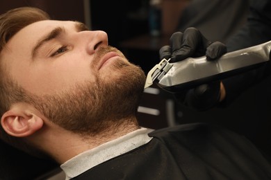 Professional hairdresser working with client in barbershop, closeup 