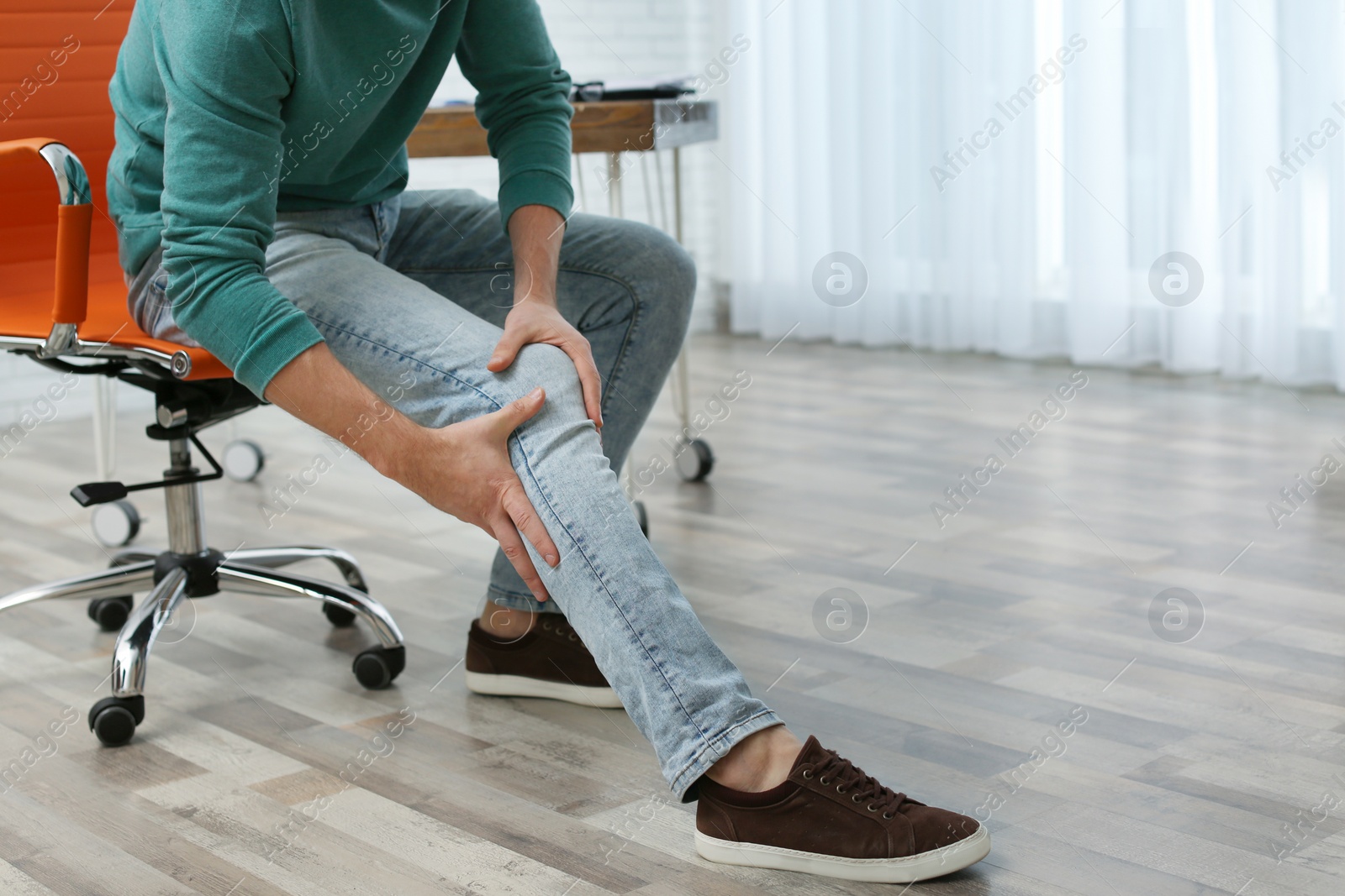 Photo of Man suffering from leg pain indoors, closeup with space for text