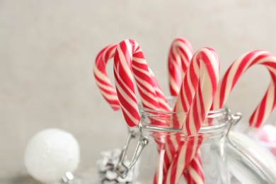Photo of Many sweet candy canes in glass jar, closeup. Traditional Christmas treat