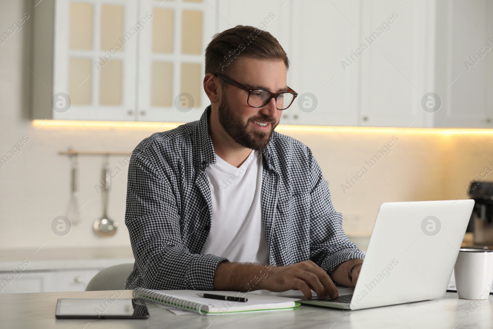 Photo of Young man working with laptop at home