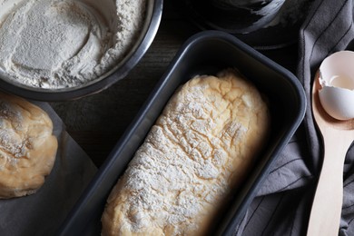 Raw dough for ciabatta and flour on wooden table, flat lay