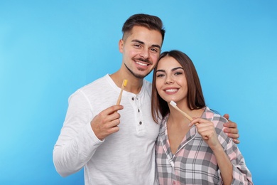 Happy couple brushing teeth on color background