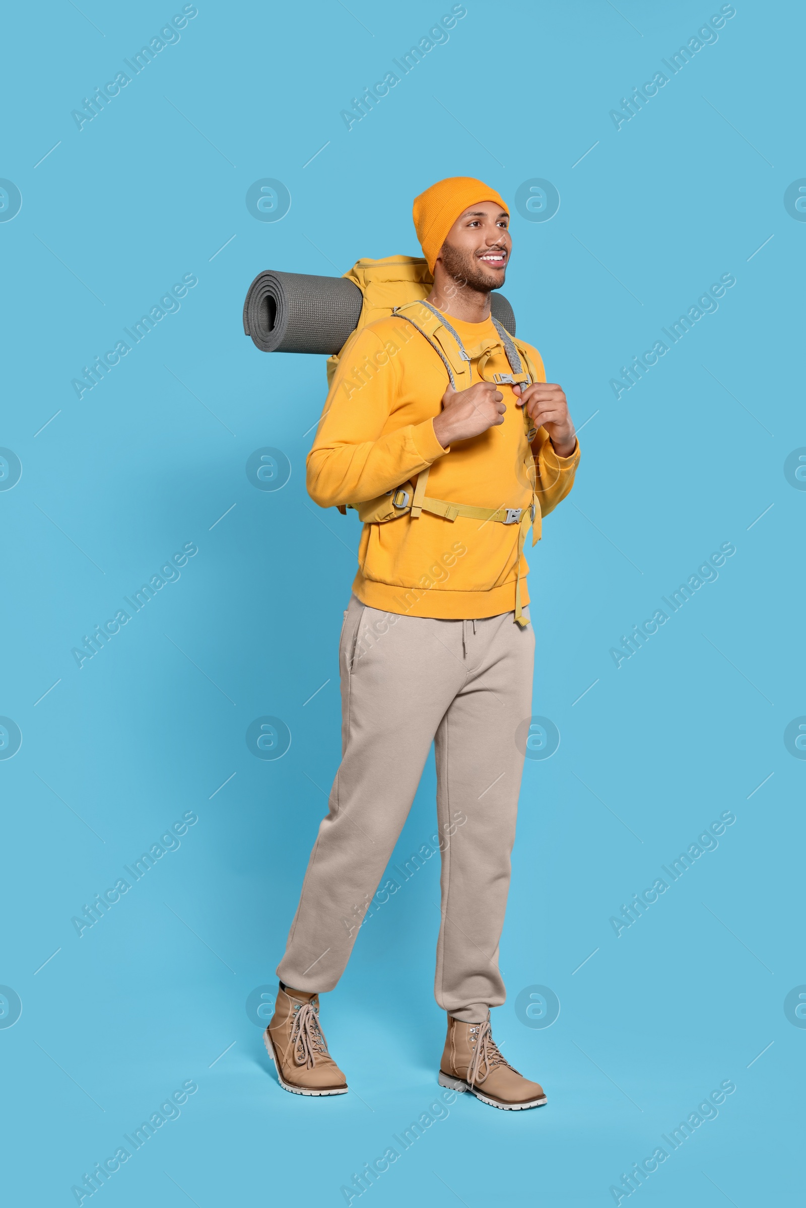 Photo of Happy tourist with backpack on light blue background