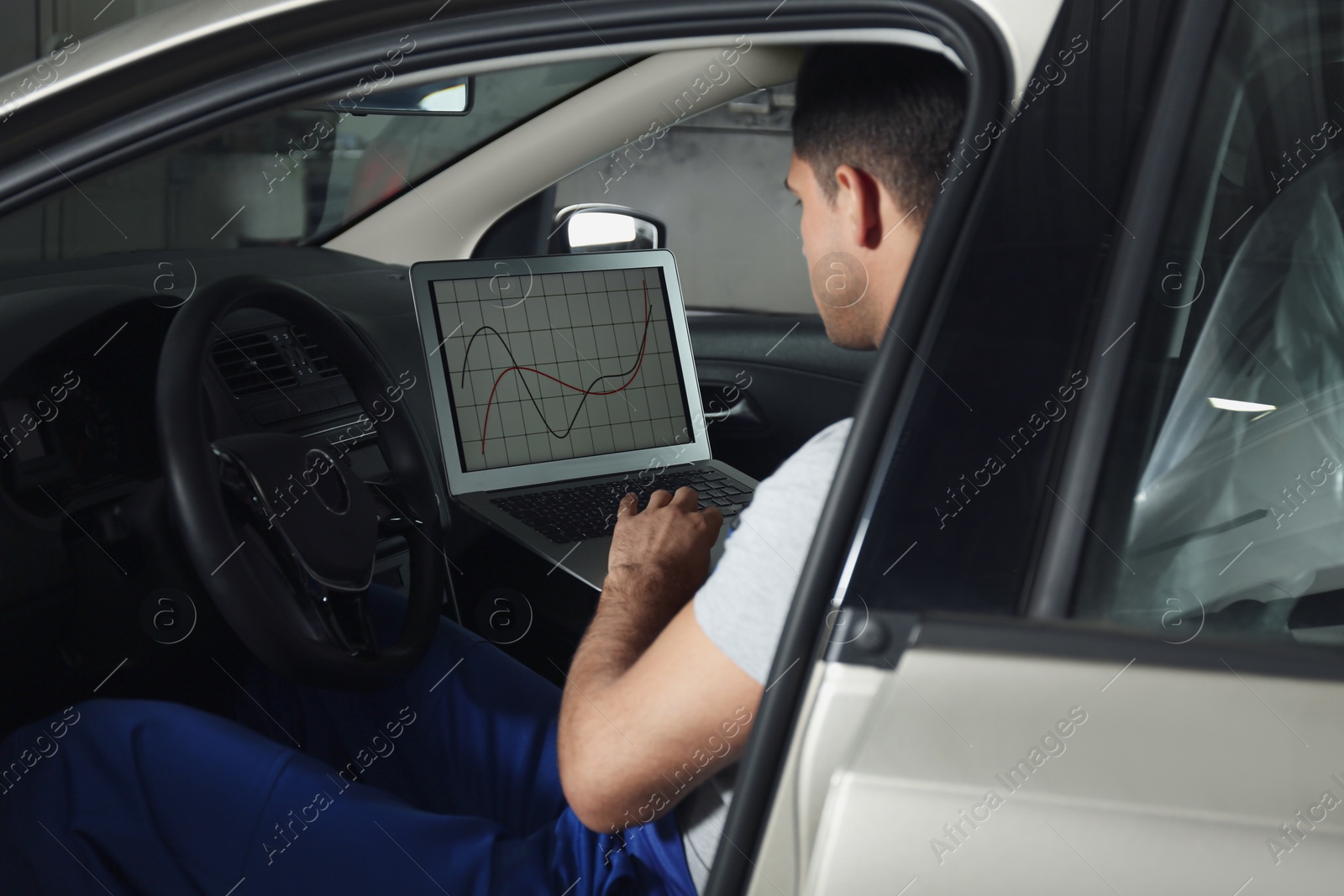 Photo of Mechanic with laptop doing car diagnostic at automobile repair shop