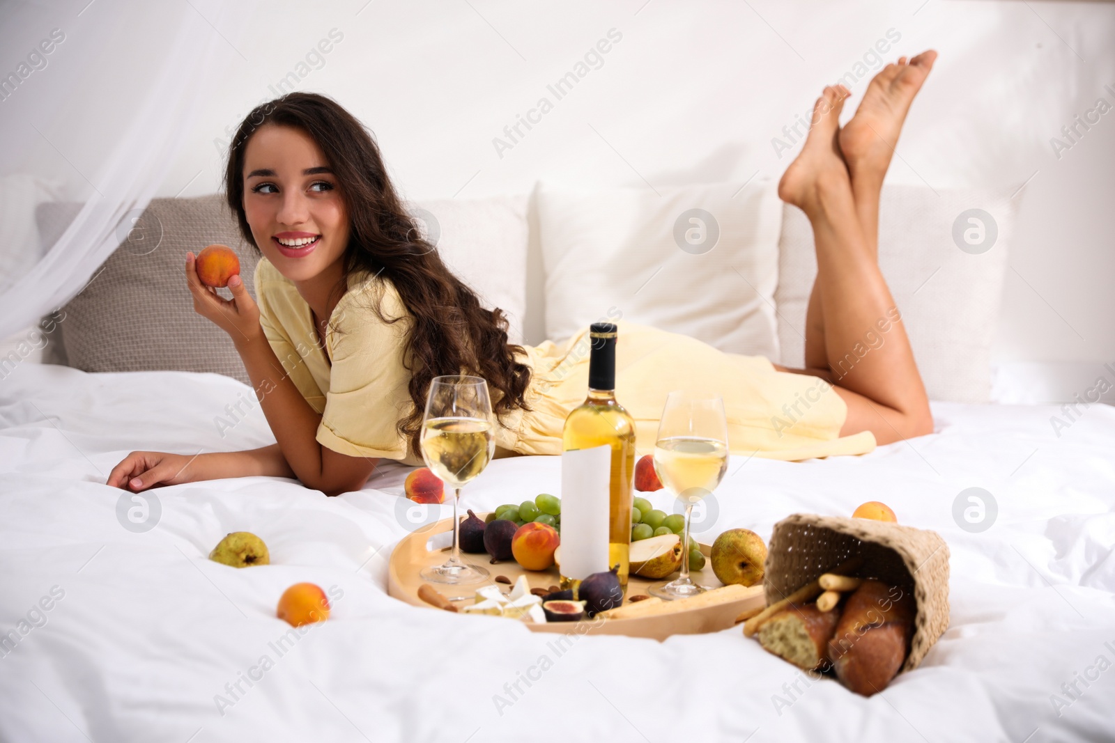 Photo of Young woman with wine and tasty food imitating picnic at home