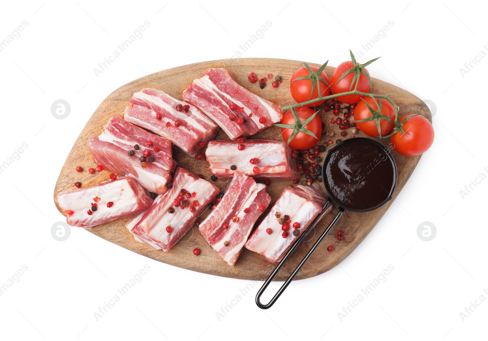 Photo of Cut raw pork ribs with peppercorns, tomatoes and sauce isolated on white, top view