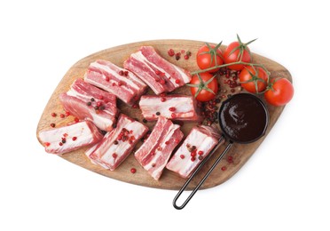 Photo of Cut raw pork ribs with peppercorns, tomatoes and sauce isolated on white, top view