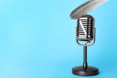 Photo of Making ASMR sounds with microphone and feather on light blue background. Space for text