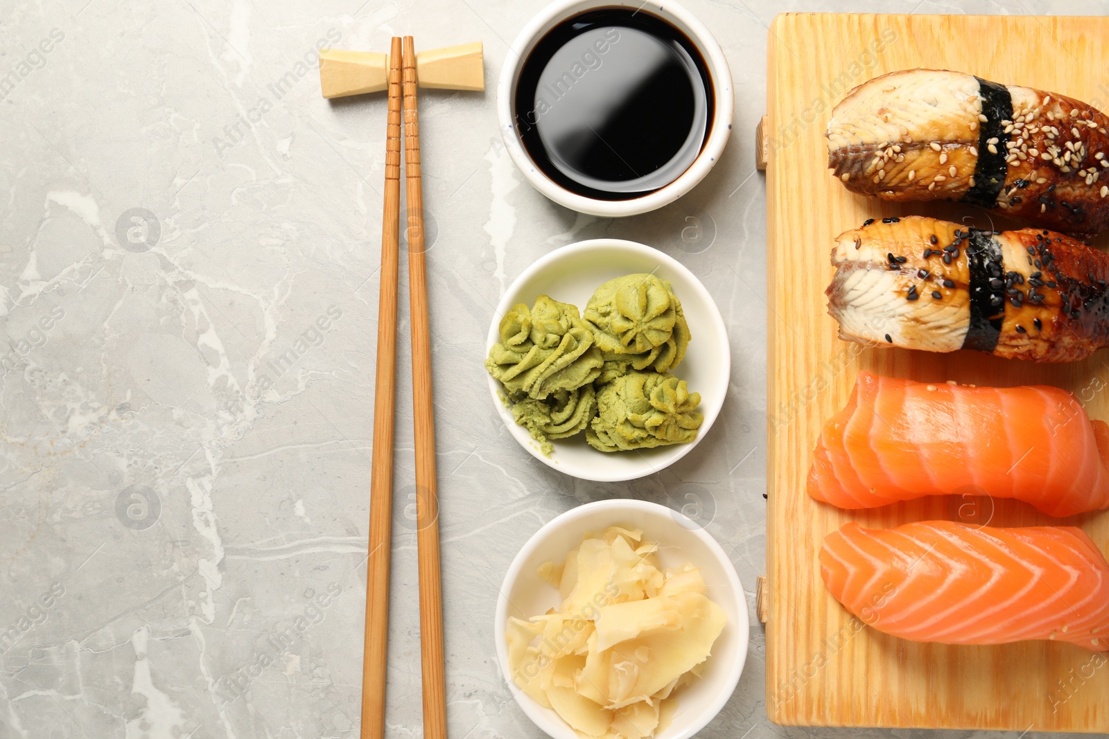 Photo of Delicious nigiri sushi served on light grey marble table, flat lay. Space for text