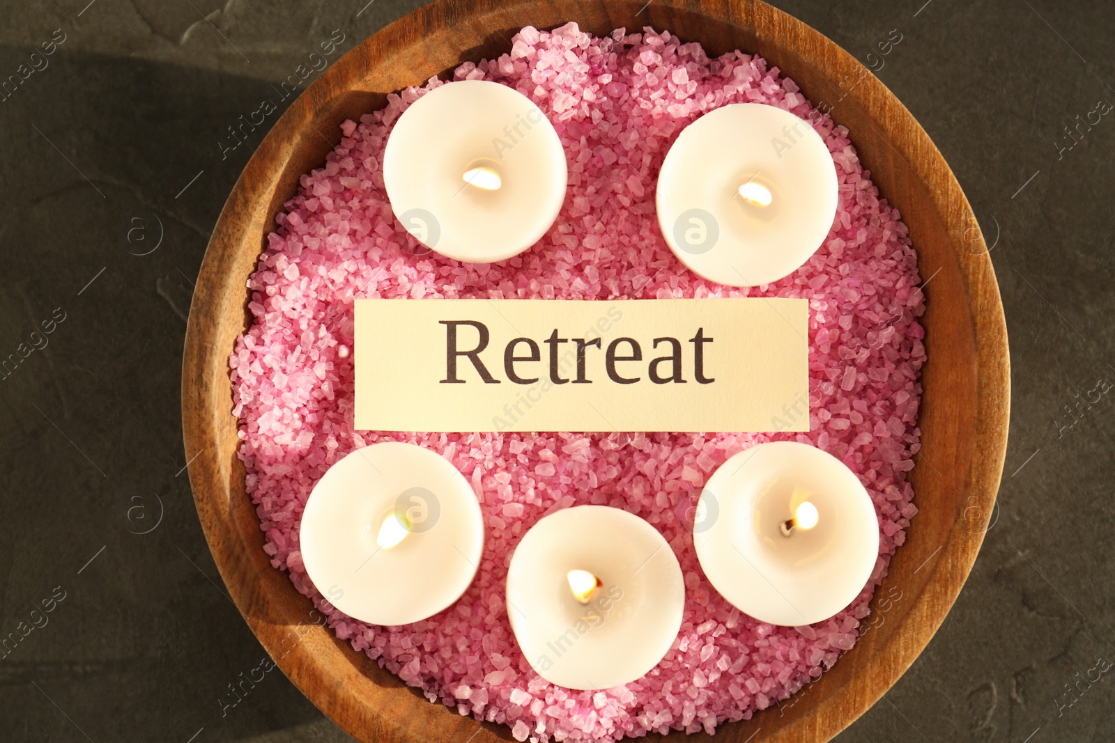 Photo of Retreat concept. Bowl with sea salt, card and burning candles on dark grey table, top view