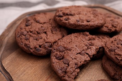 Photo of Tasty chocolate cookies on wooden board, closeup