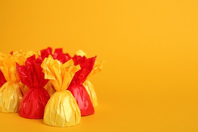 Photo of Candies in colorful wrappers on yellow background. Space for text