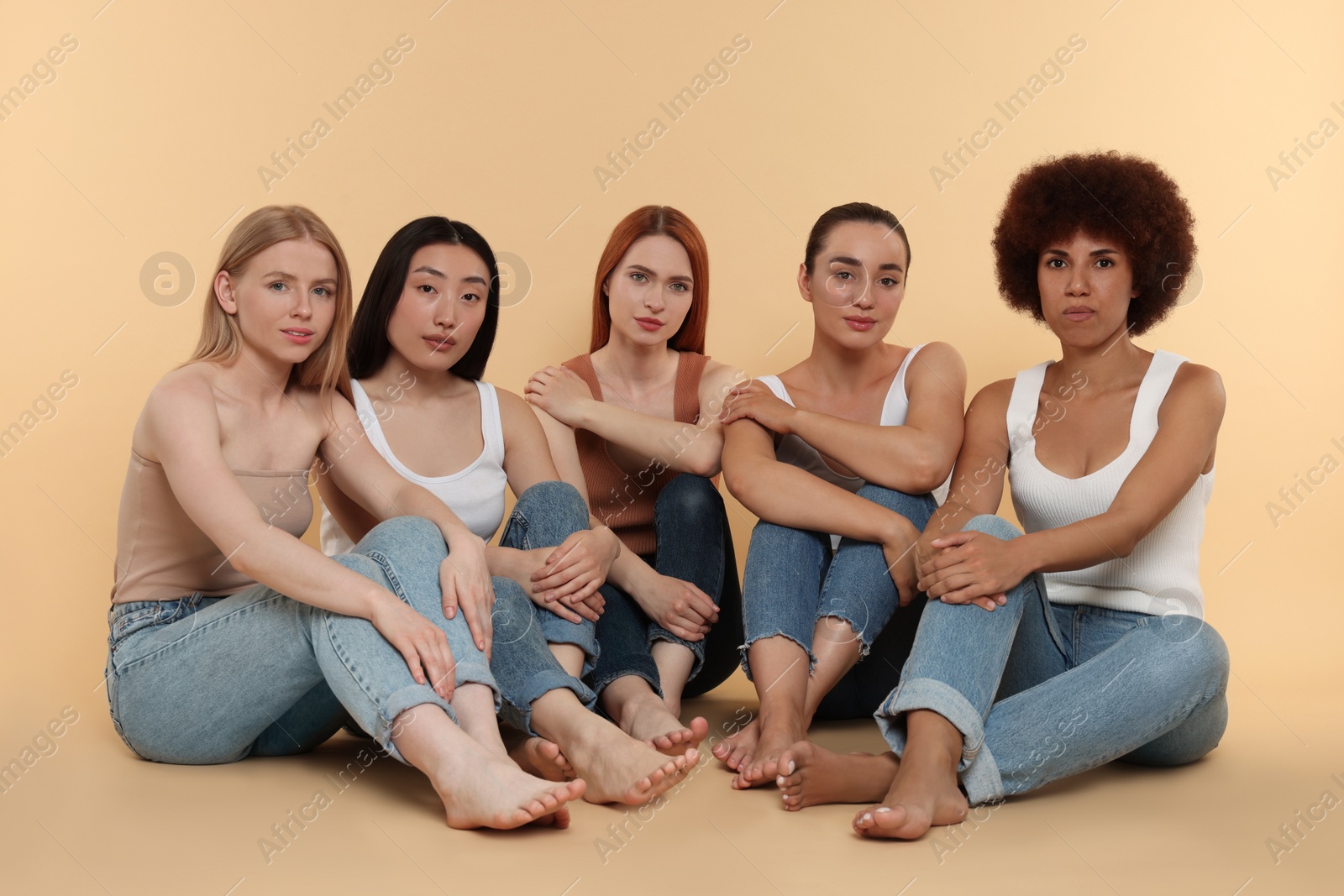 Photo of Group of beautiful young women sitting on beige background