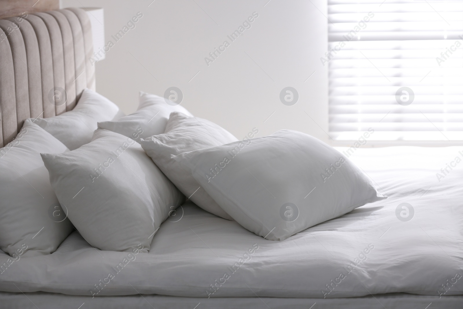 Photo of Bed with soft pillows in room. Modern interior