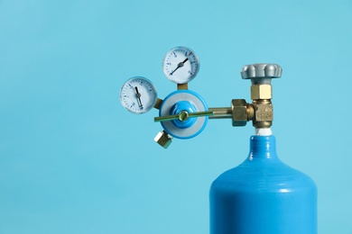 Photo of Medical oxygen tank on light blue background. Space for text