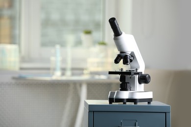 Photo of Modern medical microscope on drawer in laboratory, space for text