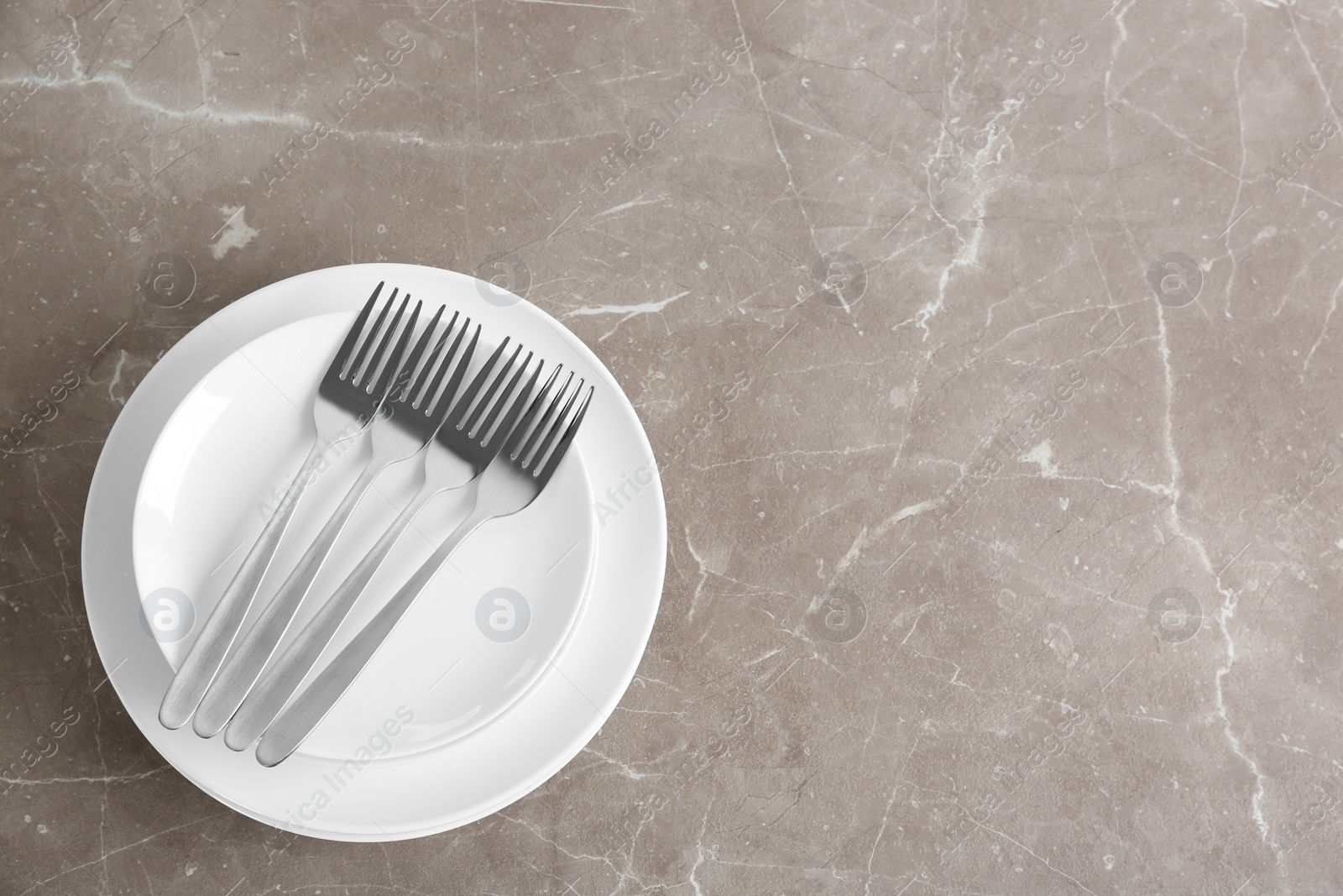 Photo of Stack of ceramic dishware with cutlery on grey background, top view