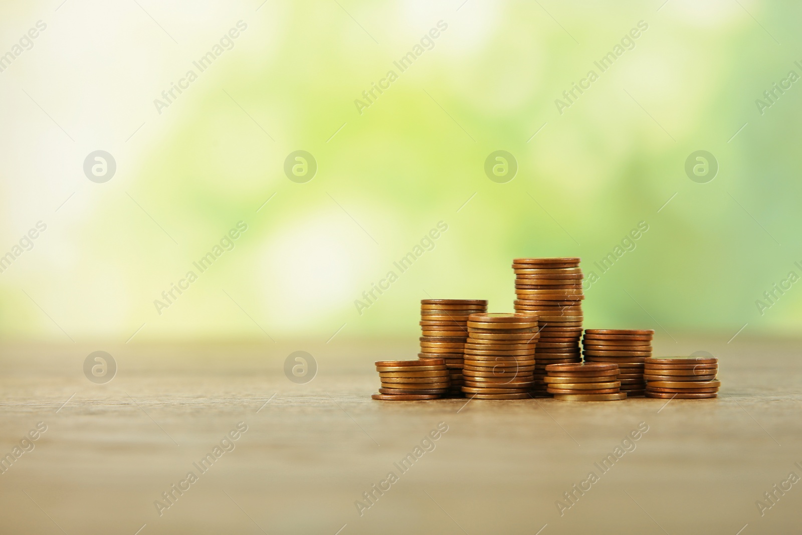 Photo of Stacks of coins on table against blurred background, space for text